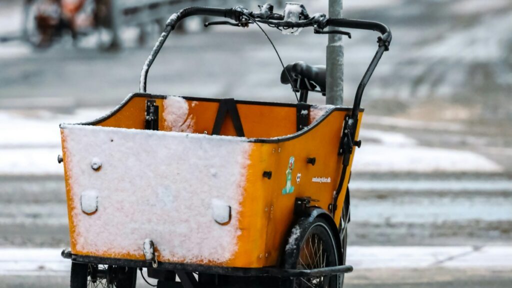 En orange og hvid cykelkurv dækket med snek.Alt beskrivelse:"Overvej at bruge en cykelkurv som denne til at transportere varer,mens du lærer'Sådan Tjener Du Penge med Facebook-Grupper'."